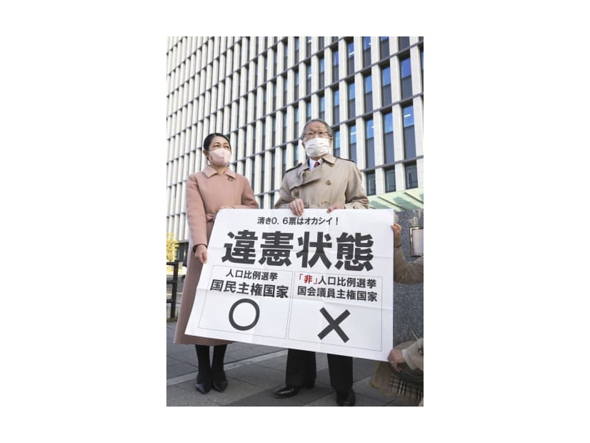 福岡高裁前で「違憲状態」と書かれた紙を掲げる原告側の升永英俊弁護士（右）ら＝21日午後