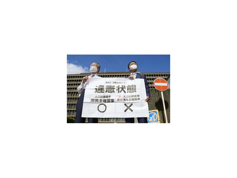参院選の「1票の格差」訴訟の判決を受け、大阪高裁前で「違憲状態」と書かれた紙を掲げる原告側の升永英俊弁護士（左）ら＝14日午後