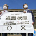 参院選の「1票の格差」訴訟の判決を受け、大阪高裁前で「違憲状態」と書かれた紙を掲げる原告側の升永英俊弁護士（左）ら＝14日午後