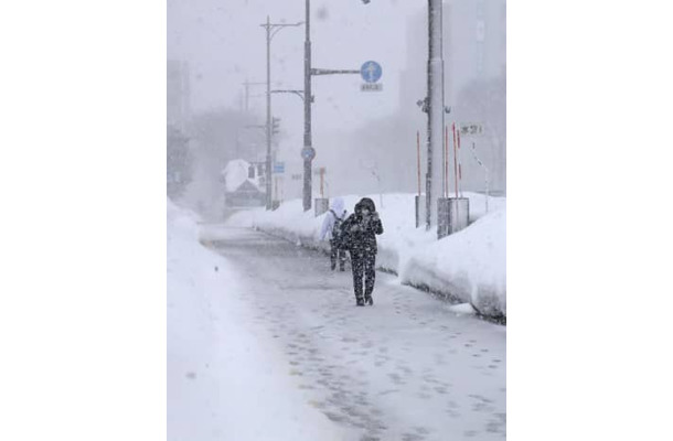 雪が降りしきる中、青森市内を歩く人＝12日午後2時22分